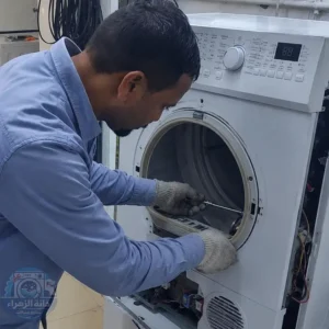 فني صيانة يقوم بتصليح نشافة ملابس داخل ورشة متخصصة وفحص الأجزاء الداخلية